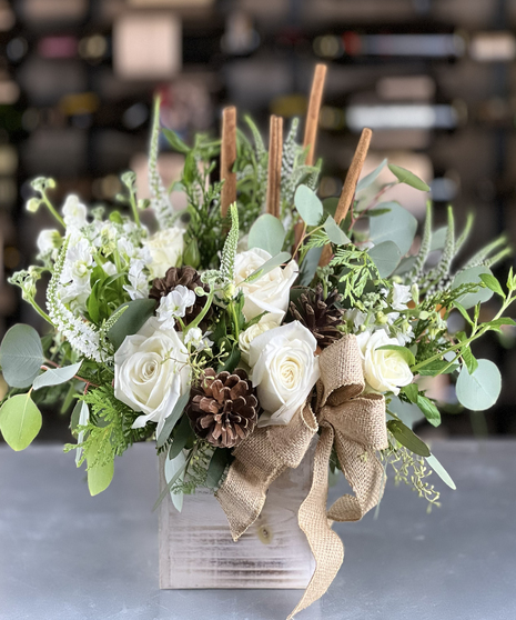 White roses, pinecones, greenery, and burlap bow arranged in rustic wooden box by Columbus Ohio Florist Griffins