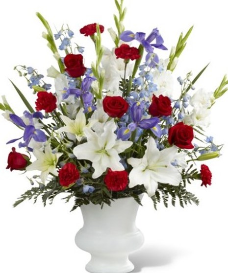 A tribute to America. Blue iris and delphinium accented with red roses and carnations, along with white lilies complete this patriotic design.