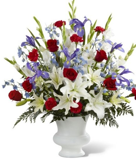 A tribute to America. Blue iris and delphinium accented with red roses and carnations, along with white lilies complete this patriotic design.