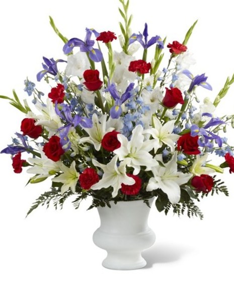 A tribute to America. Blue iris and delphinium accented with red roses and carnations, along with white lilies complete this patriotic design.