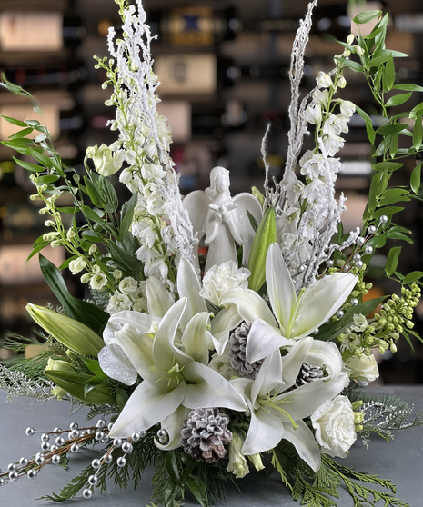 Winter floral design with white lilies, pinecones, frosted branches, and angel figurine Griffins Floral Columbus Ohio